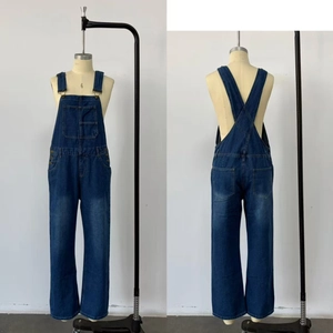 Detail of dark blue washed denim overalls with front pocket and cross-back straps