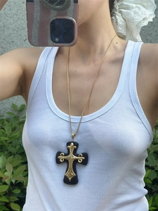 Macro view of vintage black resin cross pendant with golden baroque metal inlay