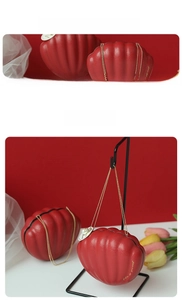 Macro detail of red shell-shaped candy box with golden chain handle and pearl tag