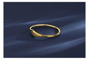 Close-up of polished gold wavy stainless steel ring on a deep blue texture background
