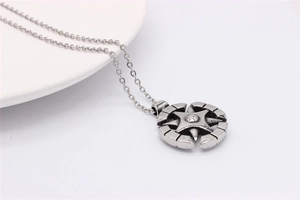Vue macro d'un collier pendentif boussole vintage argenté avec gravures d'acier