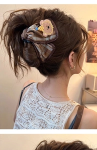 Detailed side view of a brown plaid hair claw clip with a cute cartoon bear patch on hair