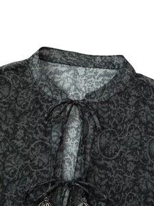 Detail of baroque print blouse featuring metallic thread and beaded tassel neck tie