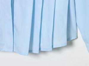 Detailed view of light blue shirt hem featuring elegant pleats and precise stitching
