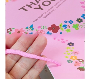 Detail of pink floral gift bag with 230g paper texture and woven handle