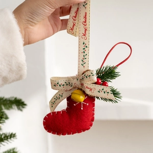 Red felt Christmas stocking ornament with festive bells and berries hanging on a tree
