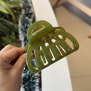 Detail of olive green acrylic hair claw clip with cutout design and gold metal spring