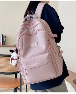 Pink ergonomic school backpack with multiple compartments shown on model in indoor setting