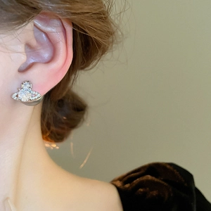 Close-up of zircon saturn stud earring with pearls and sparkling silver needle details