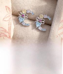 Macro shot of silver crescent heart bow earrings with colorful zircons in a jewelry box