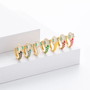 Detail view of eight colorful enamel snake-shaped earrings with green gem eyes and gold finish
