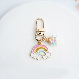 Cute rainbow and heart metal keychain with glass ball pendant on a white ceramic plate