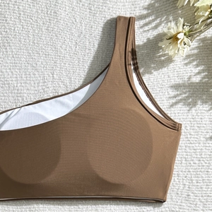 Detail of dark brown one-shoulder bikini top with ribbed texture and removable pads