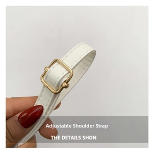Detail showing white leather adjustable shoulder strap with gold buckle and fine stitching