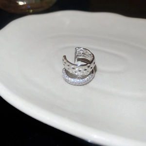 Détail d'une boucle d'oreille en argent avec texture martelée et micro-sertis en zircon