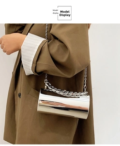 Mirror silver cylindrical bag shown crossbody with fine chain and brown blazer