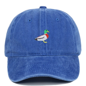 Close-up of a green duck embroidery on a washed blue vintage cotton baseball cap