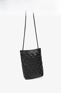 Detail of hand-woven black PU leather bucket bag featuring a minimalist knotted rope strap