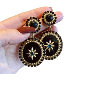 Vintage geometric gold flower earrings with black resin detail and star emblem in hand