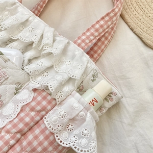 Close-up of pink plaid tote bag with floral patterns, white lace trim and diamond quilting