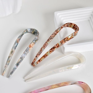 Detailed macro view of four minimalist acetate U-shaped hair pins in assorted marble colors