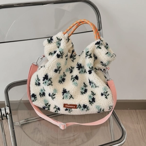 Floral lamb wool tote bag on a designer chair, showing textured fleece and woven handles