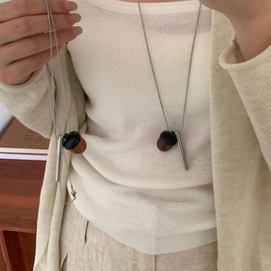 Collier bohème avec pendentif gland en métal argenté et perle de bois sur un mannequin