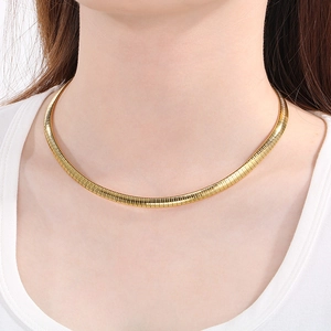 Detail of 18K gold plated flat snake bone chain necklace worn on neck with metallic texture