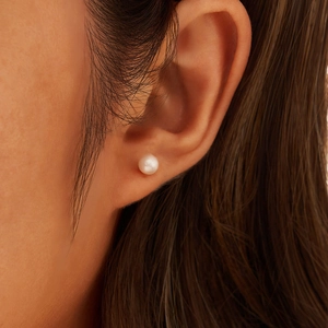 Close-up of a natural freshwater white pearl earring worn on model's earlobe
