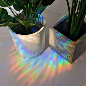 Rainbow prism effect on ground with minimalist cement planters and vibrant light reflection