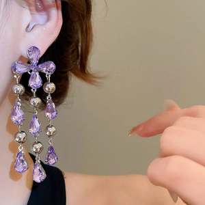 Detail of elegant purple crystal teardrop earrings with silver tassel on a model side view
