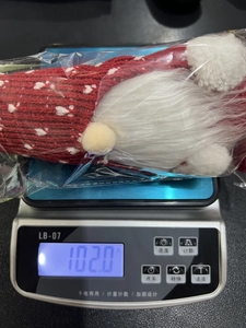 Christmas gnome doll with white beard on electronic scale weighing 102 grams