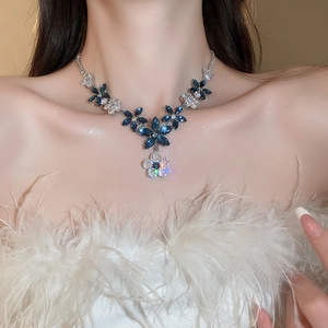 Close-up of a sparkling blue zircon flower necklace set on a model with white feathers