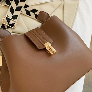 Brown leather bucket bag with wide chevron shoulder strap and gold clasp buckle