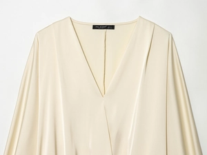 Détail d'une chemise en satin champagne avec col en V et étiquette de marque Zeal Woman