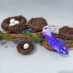 Close-up of artificial vine bird nest set with spotted white eggs and purple feather bird
