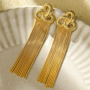 Elegant gold starfish tassel earrings with clover knot design on textured ceramic plate
