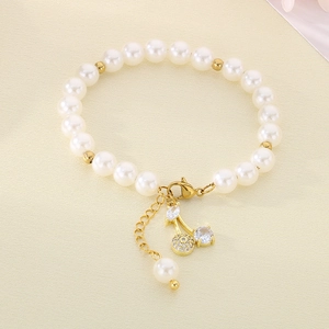 Detail of beaded pearl bracelet featuring sparkling cherry pendant and gold lobster clasp