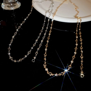 Detail of gold and silver heart link necklaces with sparkling rhinestones on black background