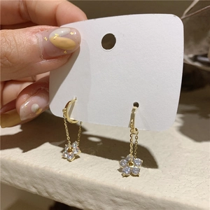 Close-up of golden flower drop earrings featuring sparkling zircon petals and sleek ear hooks