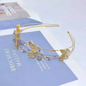 Détail d'un serre-tête doré double couche avec papillons en zircon et strass bleus