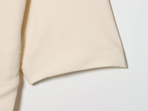Makroansicht der cremefarbenen Ärmelmanschette mit hochwertigem Stoffdetail
