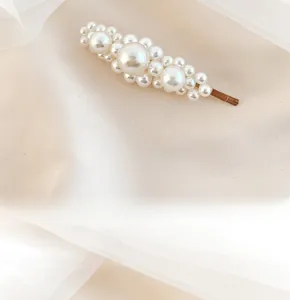 Detail of handcrafted pearl hair clip with multi-size beads on a gold metal base