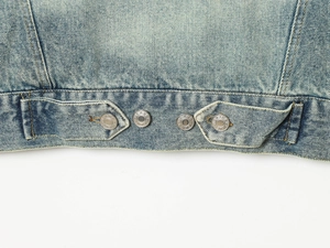 Detail of blue denim jacket hem featuring metal buttons and high-quality stitching work