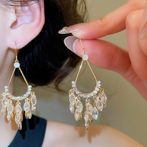 Detail showing gold teardrop tassel earrings with sparkling zircon on a person