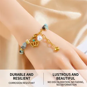 Detail of beaded bracelet with golden crown, pearl, and natural stones on silk