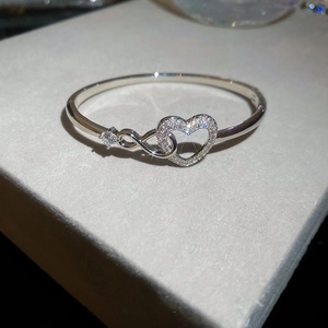 Gros plan d'un bracelet cœur en argent avec pavage en zircone et détail symbole infini