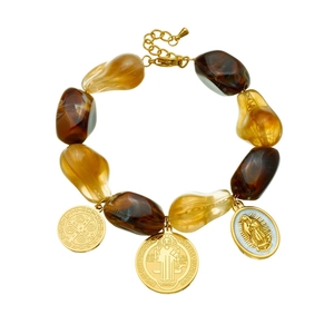 Vintage beaded bracelet with amber resin charms and golden religious saint medals on white