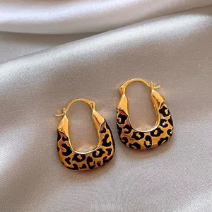 Close-up of gold-plated U-shaped hoop earrings featuring a stylish leopard enamel pattern
