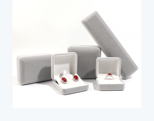 Gros plan d'écrins à bijoux en velours gris clair pour bagues et colliers, doublure blanche